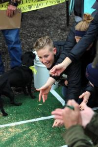 Littleton’s Taylor Bailey awaits her dog at the finish line. Meanwhile, the dog to her left makes quick work of her unattended hot dog.