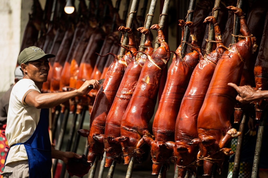 A worker removes hair from roasted pigs for sale along a street in Manila on December 24, 2016. Lechon, or roasted pig, is regular fare at Philippine festivities, especially during the Christmas season.